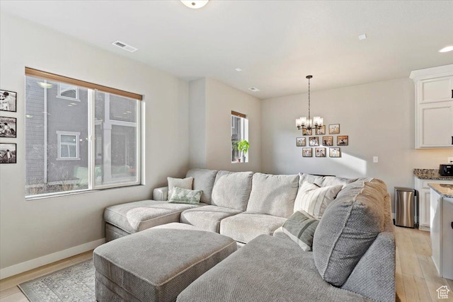 living room featuring visible vents, baseboards, a chandelier, and light wood-type flooring