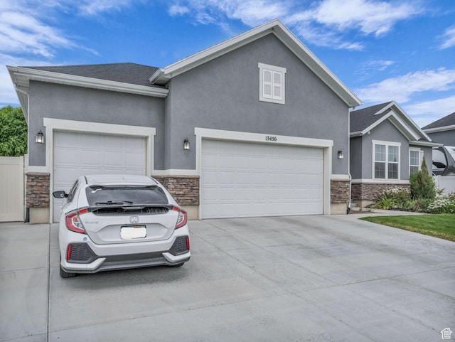 13456 S Rowell Dr, Herriman, UT 84096 - view of front facade featuring stone siding, driveway, stucco siding, and an attached garage