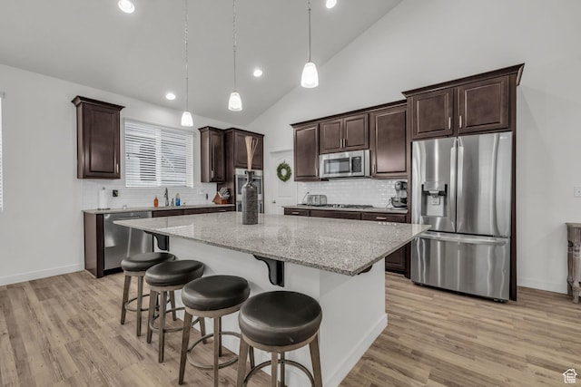 13456 S Rowell Dr, Herriman, UT 84096 - kitchen featuring appliances with stainless steel finishes, vaulted ceiling, a kitchen island, dark brown cabinets, and light wood-type flooring