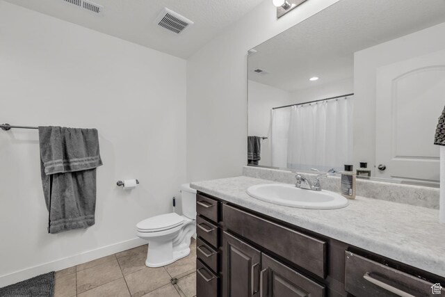 bathroom featuring walk in shower, toilet, a textured ceiling, vanity, and tile patterned flooring