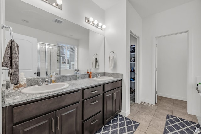 bathroom with a shower with door, vanity, and tile patterned floors