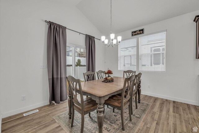 dining area with lofted ceiling, a notable chandelier, and light hardwood / wood-style floors