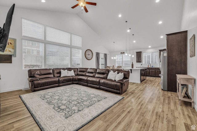 living room with ceiling fan, high vaulted ceiling, a healthy amount of sunlight, and light wood-type flooring