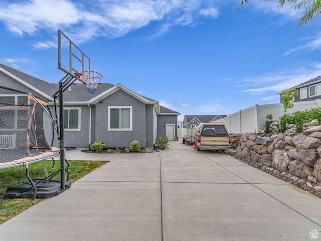 13456 S Rowell Dr, Herriman, UT 84096 - view of home's exterior with a trampoline, stucco siding, and concrete driveway