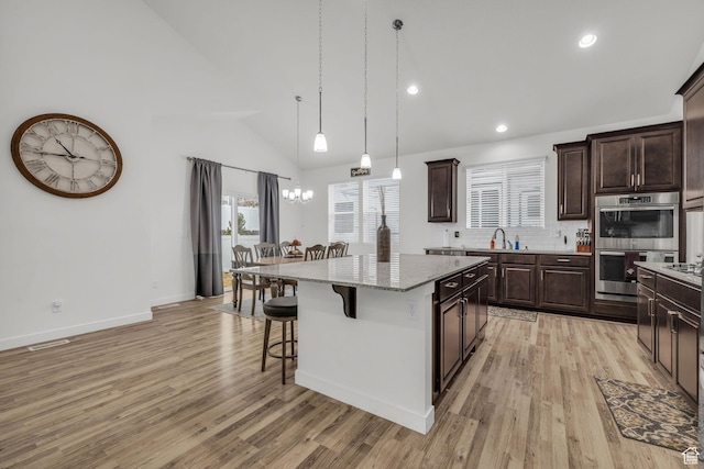 13456 S Rowell Dr, Herriman, UT 84096 - kitchen featuring stainless steel double oven, a kitchen breakfast bar, a center island, light wood-style flooring, and dark brown cabinets