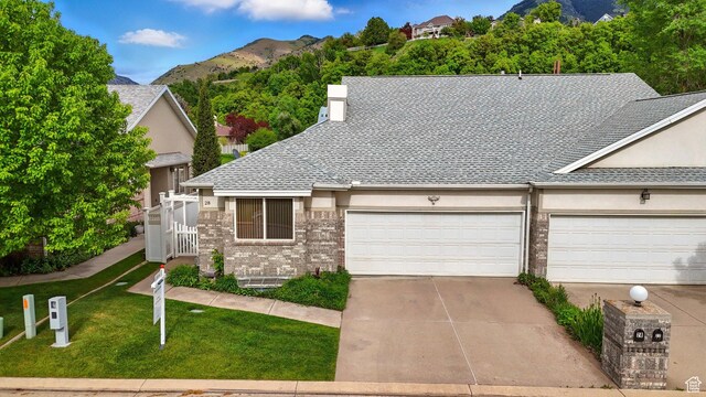 28 N River Pointe Dr, Logan, UT 84321 - view of front facade featuring concrete driveway, a front yard, a mountain view, a shingled roof, and an attached garage