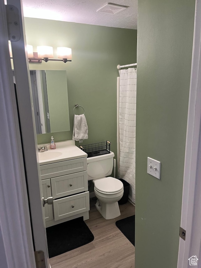 3134 S Buena Verde Ln, Magna, UT 84044 - bathroom featuring curtained shower, a textured ceiling, wood-type flooring, vanity, and toilet