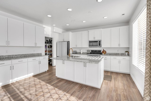 1025 S 850 W, American Fork, UT 84003 - kitchen with white cabinets, a center island with sink, light stone countertops, and stainless steel appliances