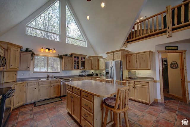 2310 S Sweetwater Pkwy Unit 5, Garden City, UT 84028 - kitchen featuring stainless steel appliances, high vaulted ceiling, light brown cabinets, a center island, and glass insert cabinets