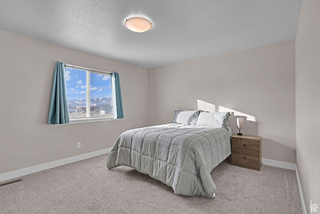 bedroom featuring light colored carpet and a textured ceiling