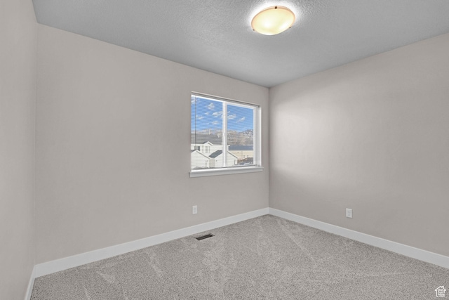 unfurnished room with carpet and a textured ceiling