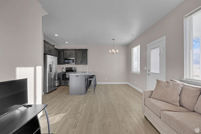 living room featuring a wealth of natural light, light hardwood / wood-style flooring, a chandelier, and sink