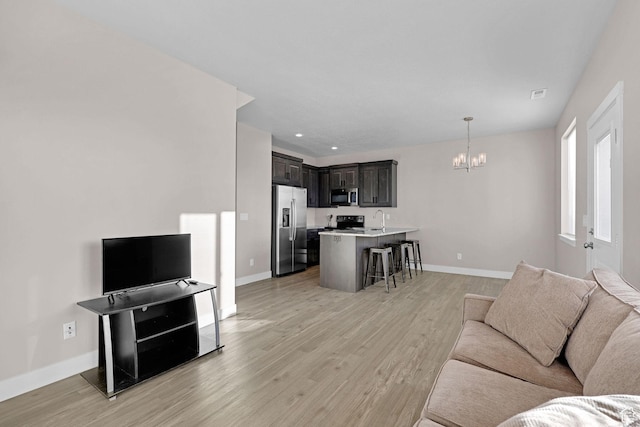 living room with light hardwood / wood-style flooring, sink, and a chandelier