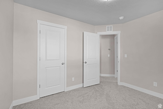 unfurnished bedroom with a textured ceiling and light carpet
