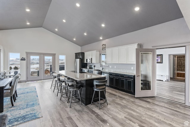 2923 S Country Club Way Unit 46, Garden City, UT 84028 - kitchen featuring high vaulted ceiling, appliances with stainless steel finishes, a kitchen bar, a kitchen island, and light stone counters