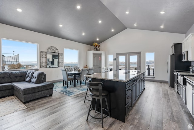 2923 S Country Club Way Unit 46, Garden City, UT 84028 - kitchen with appliances with stainless steel finishes, a kitchen island, light stone countertops, open floor plan, and high vaulted ceiling