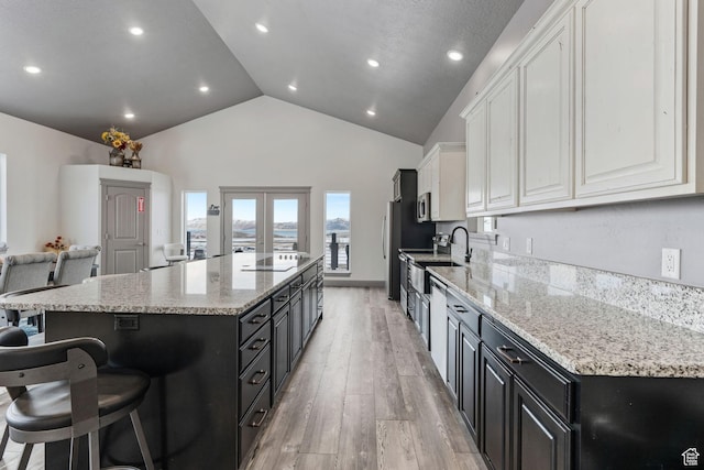 2923 S Country Club Way Unit 46, Garden City, UT 84028 - kitchen featuring dark cabinetry, white cabinets, a spacious island, a breakfast bar, and light wood-type flooring