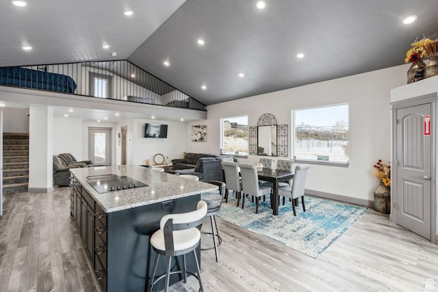 2923 S Country Club Way Unit 46, Garden City, UT 84028 - kitchen featuring open floor plan, lofted ceiling, black electric cooktop, light stone countertops, and light wood-type flooring