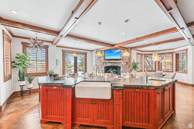 kitchen with pendant lighting, a large island, beam ceiling, and a fireplace