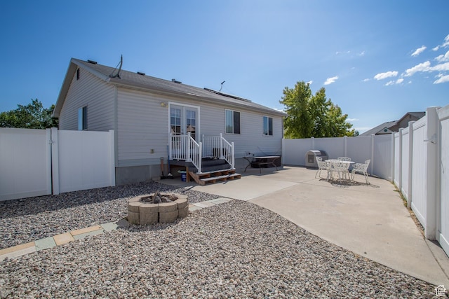 back of house with a gate, a fenced backyard, a patio area, and an outdoor fire pit