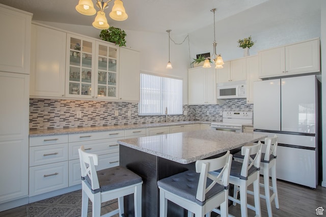 kitchen featuring decorative backsplash, white appliances, a chandelier, a sink, and vaulted ceiling