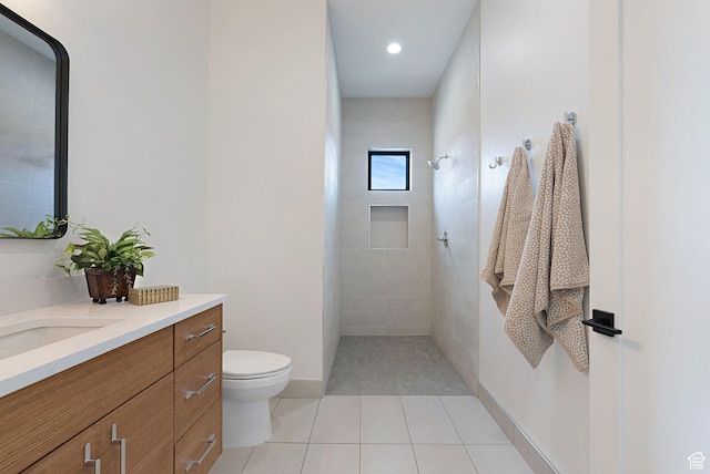 bathroom featuring toilet, vanity, tiled shower, and tile patterned floors