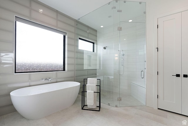 bathroom featuring tile patterned flooring, tile walls, and independent shower and bath