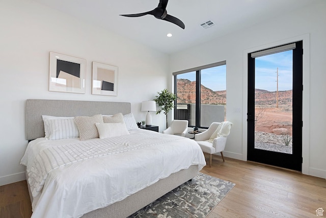 bedroom with a mountain view, light wood-type flooring, access to exterior, and ceiling fan