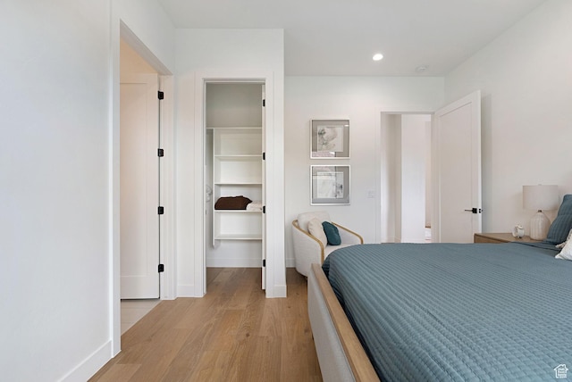 bedroom with a closet, a spacious closet, and light hardwood / wood-style flooring