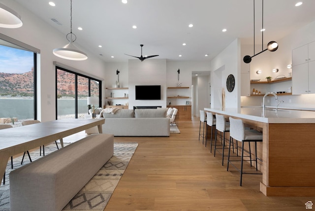 living room with ceiling fan, light wood-type flooring, and sink