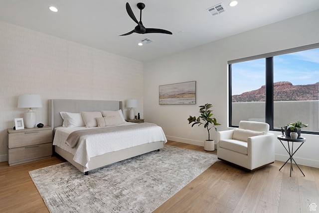 bedroom with ceiling fan, a mountain view, and light wood-type flooring