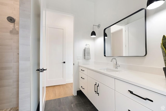 bathroom with vanity, a tile shower, and wood-type flooring