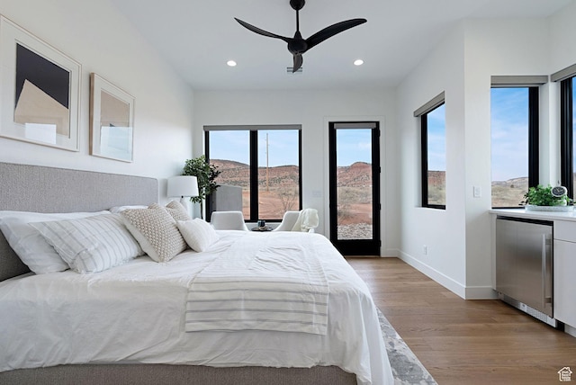 bedroom featuring a mountain view, refrigerator, light hardwood / wood-style floors, and ceiling fan
