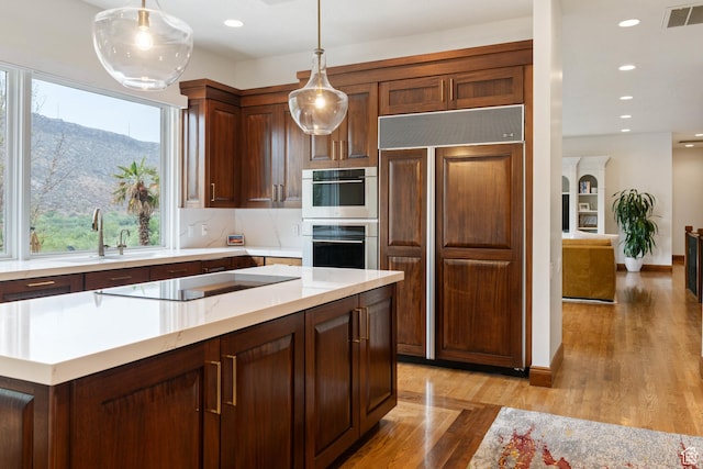 2712 S Rio Vista Dr, St George, UT 84790 - kitchen featuring stainless steel double oven, a mountain view, pendant lighting, black electric cooktop, and paneled built in fridge