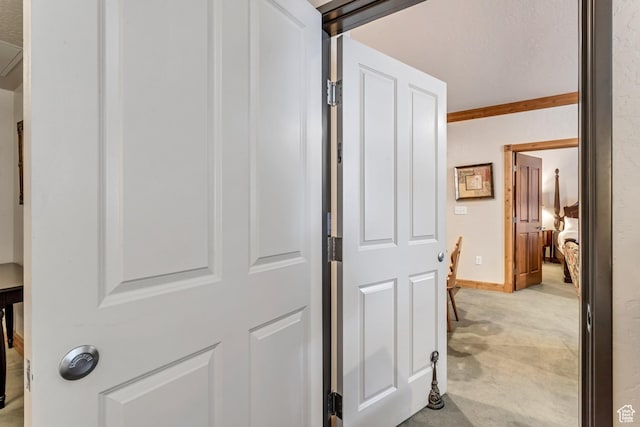 corridor featuring light colored carpet and ornamental molding