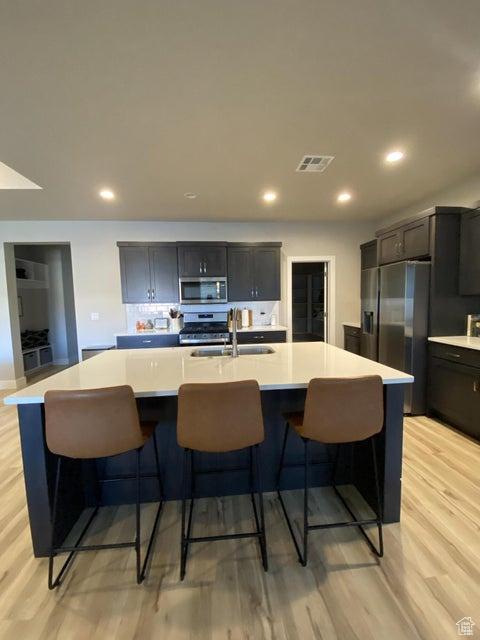 kitchen featuring a large island with sink, stainless steel appliances, light hardwood / wood-style floors, and sink