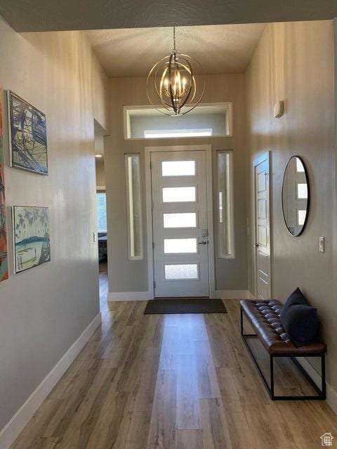 foyer entrance featuring wood-type flooring and an inviting chandelier