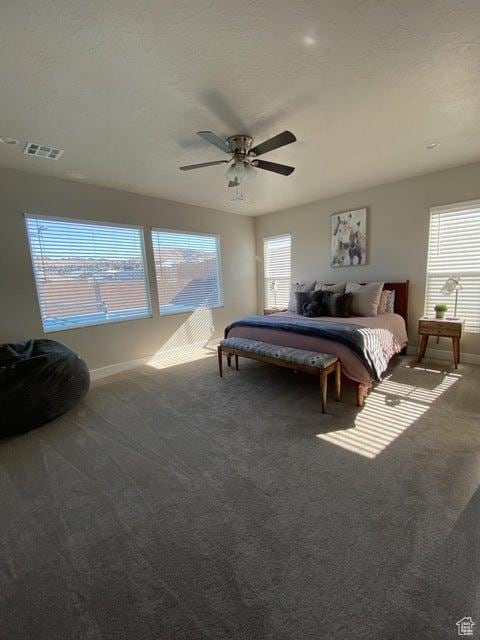 carpeted bedroom featuring ceiling fan and a textured ceiling
