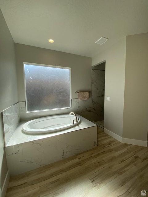 bathroom with hardwood / wood-style floors and shower with separate bathtub