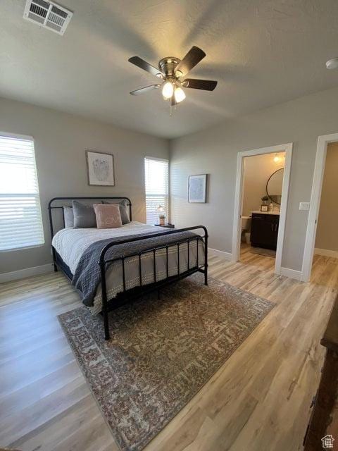 bedroom with multiple windows, ceiling fan, ensuite bathroom, and light wood-type flooring