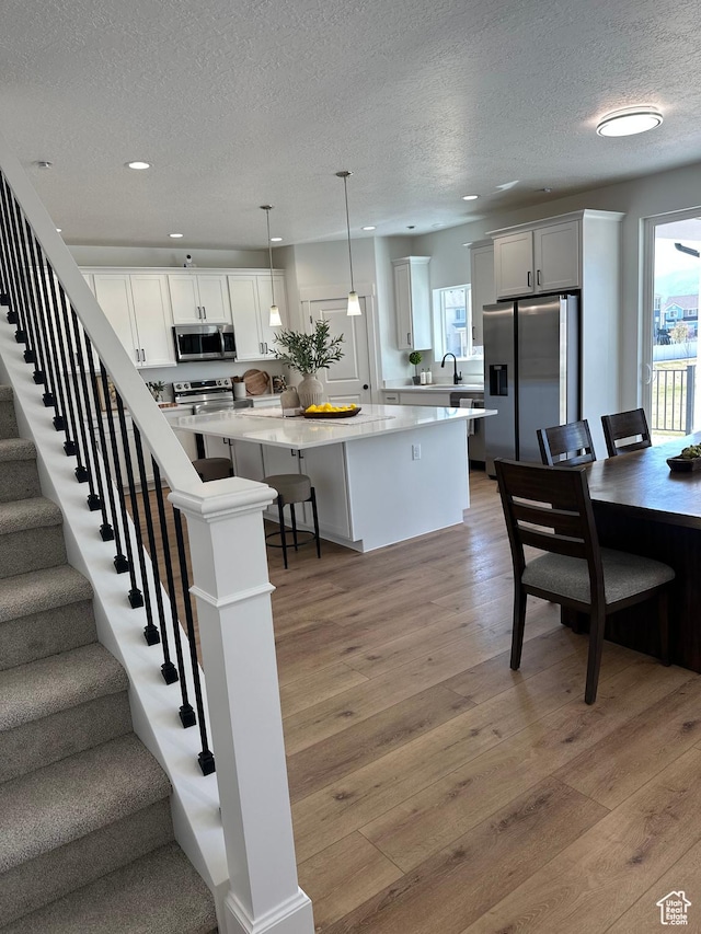 7949 N Bristlecone Rd Unit 206, Eagle Mountain, UT 84005 - kitchen featuring plenty of natural light, a textured ceiling, a center island, and stainless steel appliances