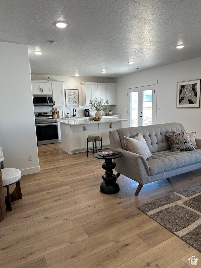 7949 N Bristlecone Rd Unit 206, Eagle Mountain, UT 84005 - living area with light wood-style flooring, a textured ceiling, and french doors