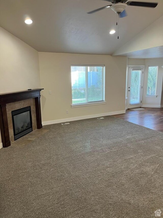 unfurnished living room featuring ceiling fan, lofted ceiling, and dark colored carpet