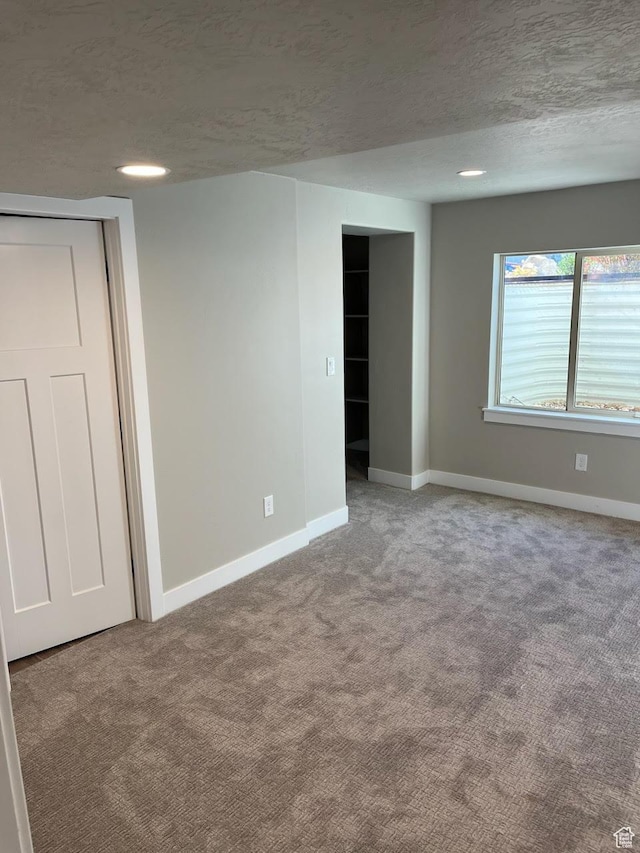 carpeted spare room featuring a textured ceiling