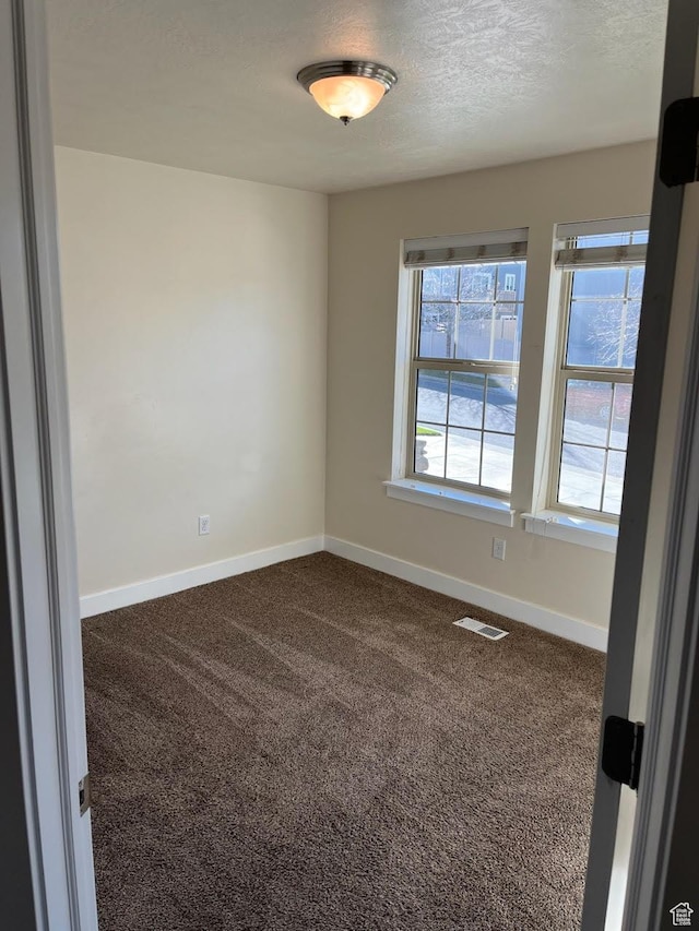 carpeted empty room with a textured ceiling