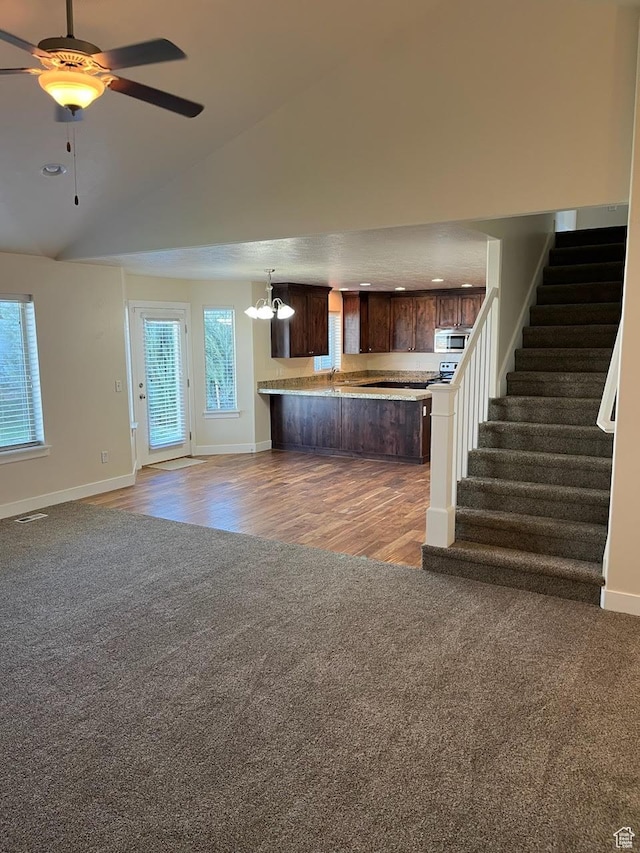 unfurnished living room with vaulted ceiling and ceiling fan with notable chandelier