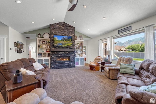 carpeted living room featuring a textured ceiling, vaulted ceiling, ceiling fan, and a stone fireplace