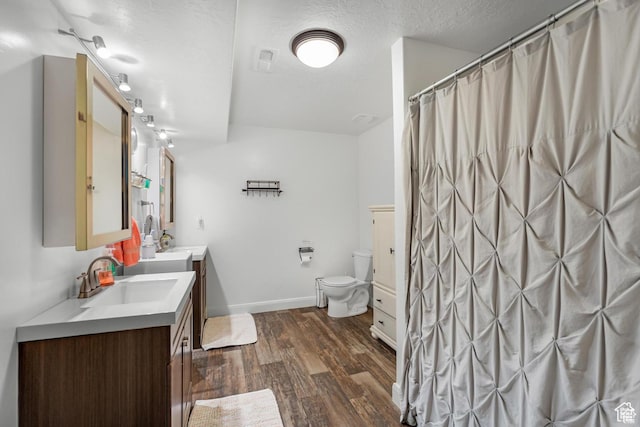 bathroom with a shower with shower curtain, vanity, a textured ceiling, wood-type flooring, and toilet