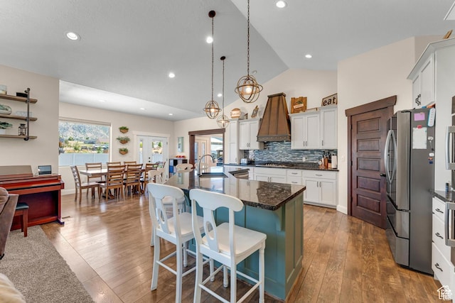 kitchen with hanging light fixtures, vaulted ceiling, a kitchen bar, white cabinets, and appliances with stainless steel finishes