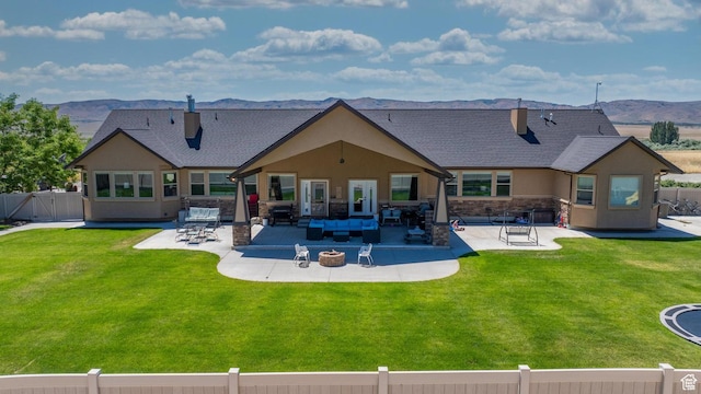 back of house with a patio area, a mountain view, a yard, and an outdoor living space with a fire pit